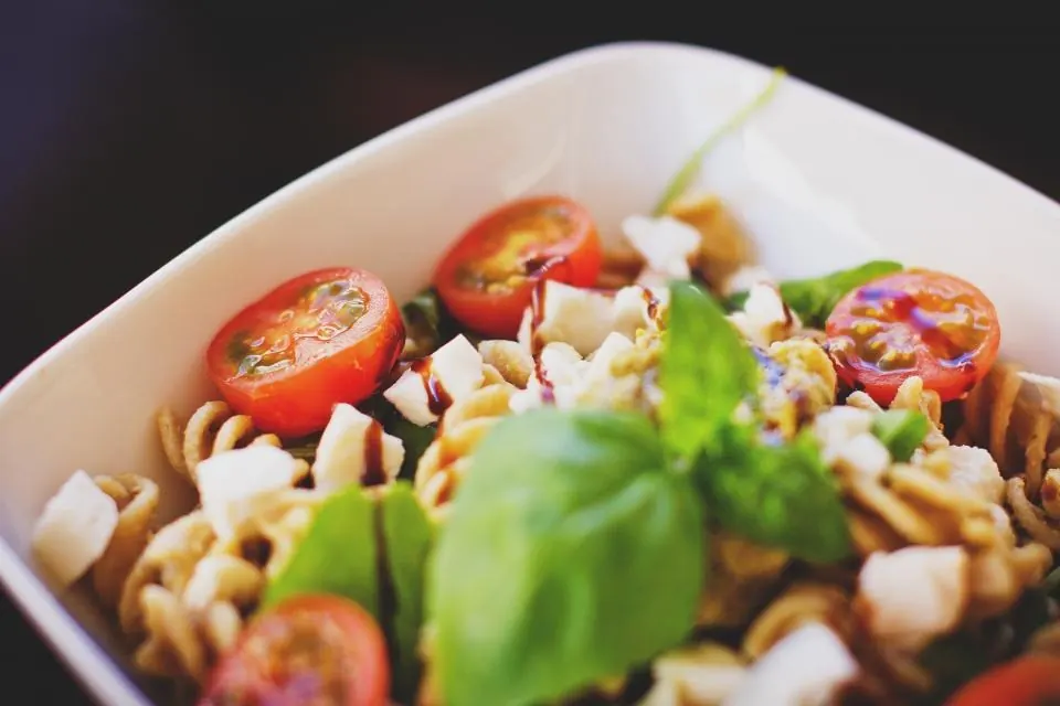 Ensalada de pasta con tomates cherry, mozzarella y hojas de albahaca